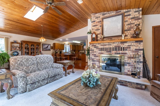 carpeted living room with wood ceiling, ceiling fan, lofted ceiling with skylight, and a brick fireplace