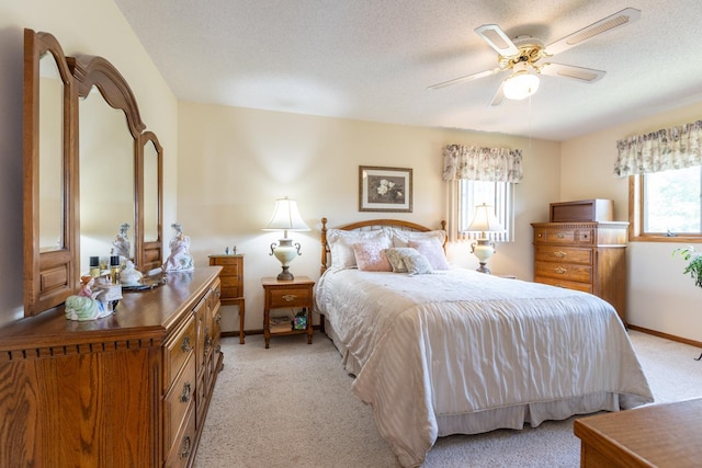 carpeted bedroom with ceiling fan and a textured ceiling