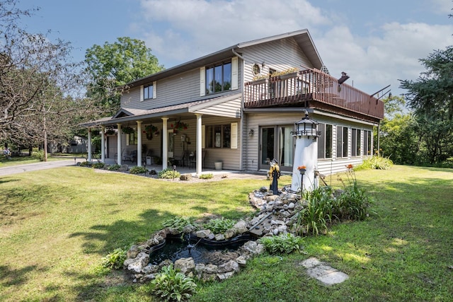 rear view of house with a wooden deck and a lawn