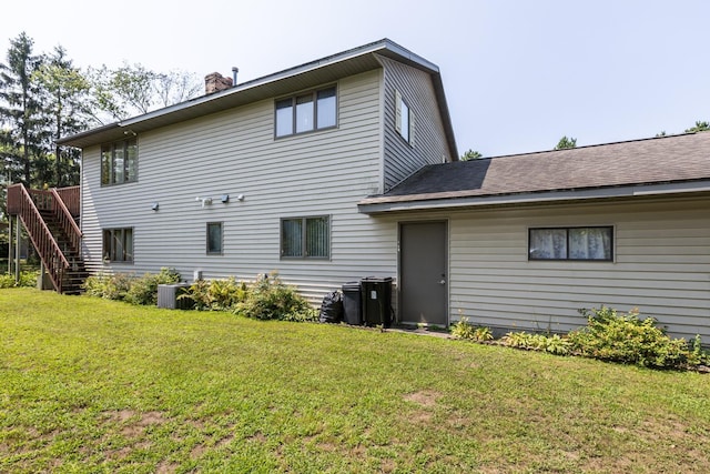 back of property with central AC unit and a lawn