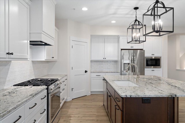 kitchen with tasteful backsplash, stainless steel appliances, a center island with sink, light hardwood / wood-style floors, and white cabinetry