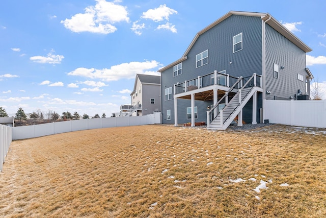 rear view of house featuring a fenced backyard, stairway, and a deck