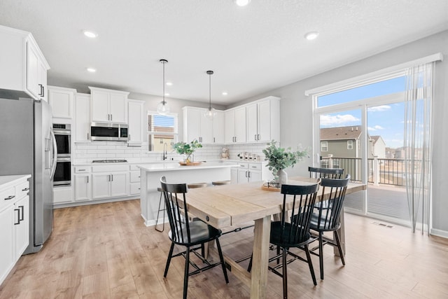 kitchen with appliances with stainless steel finishes, light wood-type flooring, and backsplash