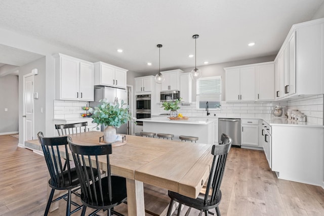 dining space featuring light wood-style floors, baseboards, and recessed lighting