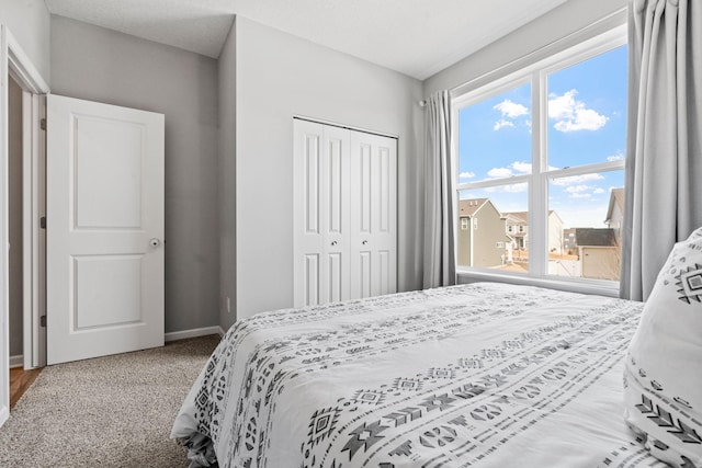 bedroom with carpet floors, baseboards, and a closet