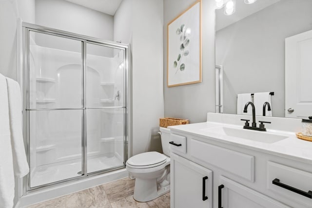 full bath featuring a stall shower, vanity, and toilet