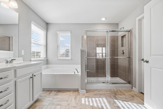 bathroom with a stall shower, a garden tub, a textured ceiling, and vanity