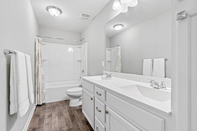 bathroom with a textured ceiling, wood finished floors, a sink, and visible vents