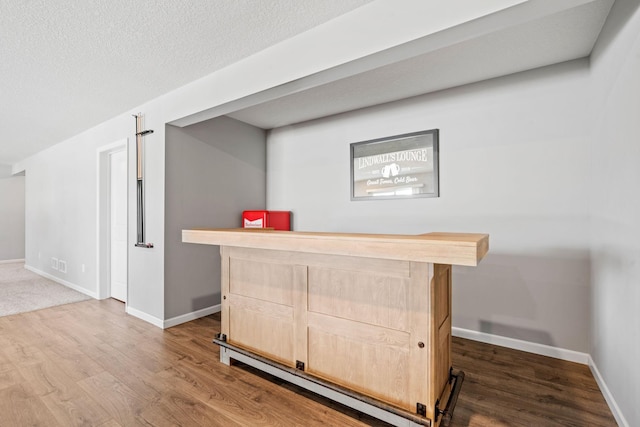 bar with visible vents, a bar, baseboards, and wood finished floors