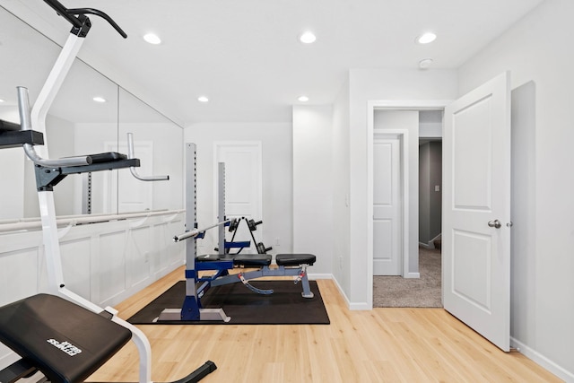 exercise area with baseboards, light wood finished floors, and recessed lighting