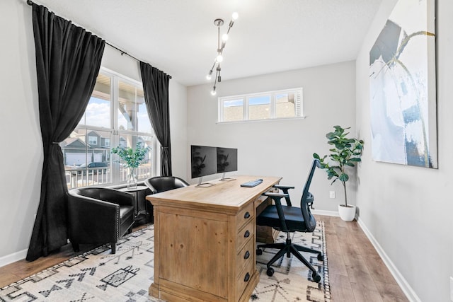 office featuring light wood finished floors, plenty of natural light, and baseboards