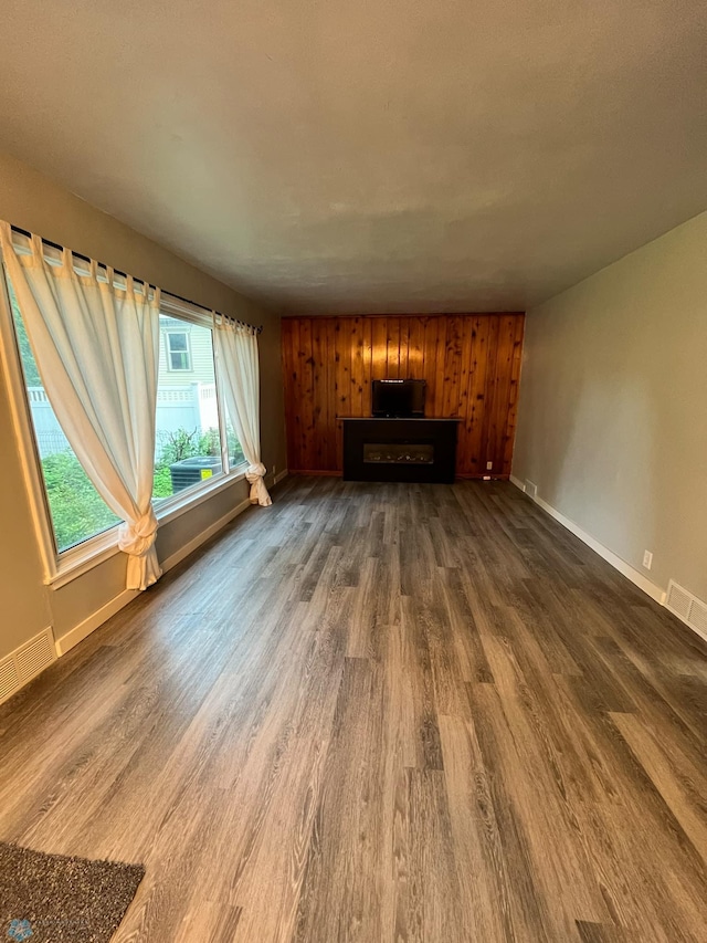 unfurnished living room with wood walls and dark hardwood / wood-style flooring