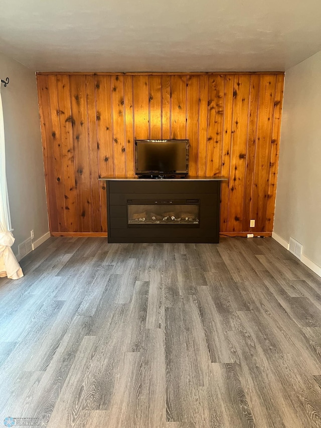 unfurnished living room with dark hardwood / wood-style floors and wood walls