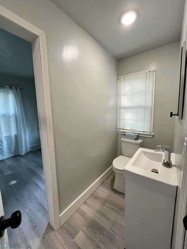 bathroom with wood-type flooring, vanity, and toilet