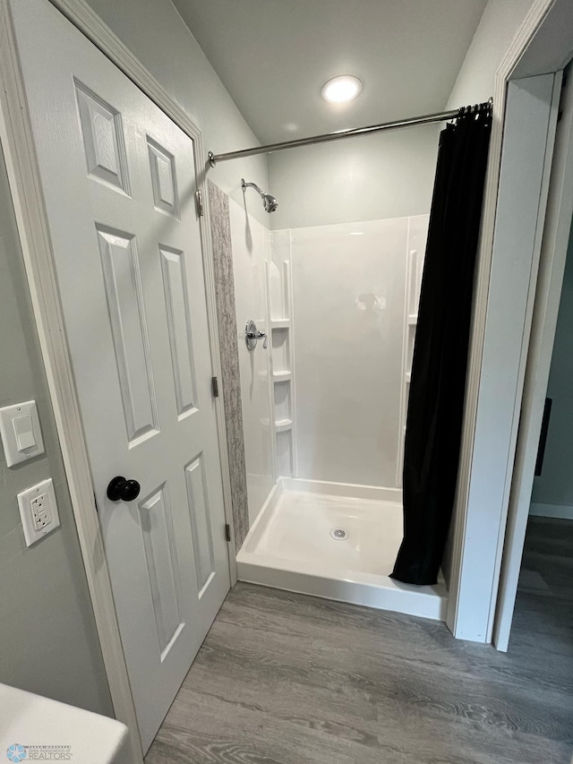 bathroom with a shower with shower curtain and wood-type flooring