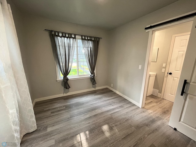 empty room with a barn door and hardwood / wood-style flooring