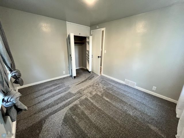 unfurnished bedroom featuring dark carpet and a closet