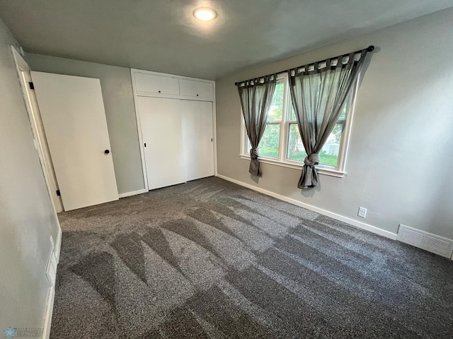 unfurnished bedroom featuring dark carpet and a closet