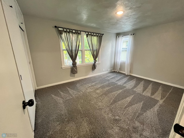 carpeted empty room featuring a textured ceiling