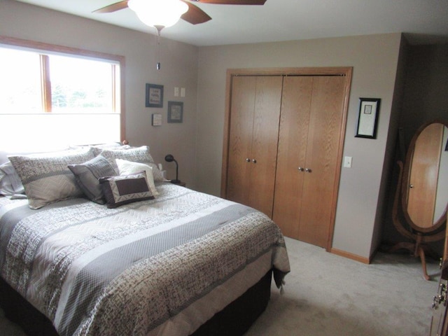 bedroom featuring light colored carpet, a closet, a ceiling fan, and baseboards