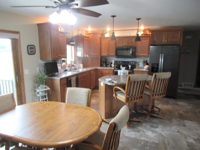 kitchen with a ceiling fan, hanging light fixtures, visible vents, a sink, and appliances with stainless steel finishes