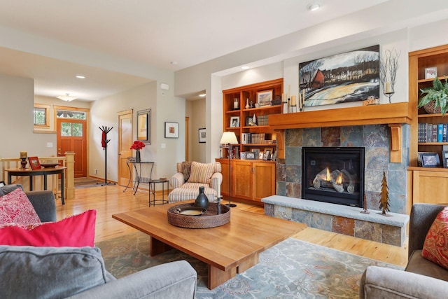 living area with built in shelves, baseboards, light wood-type flooring, recessed lighting, and a fireplace