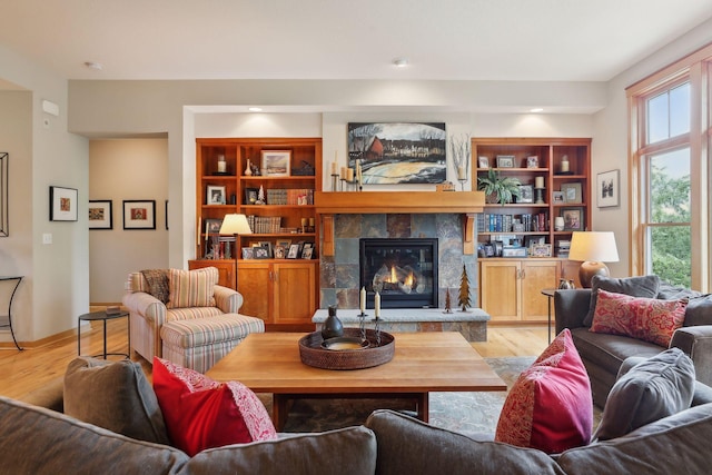 living room with baseboards, built in shelves, wood finished floors, and a tile fireplace