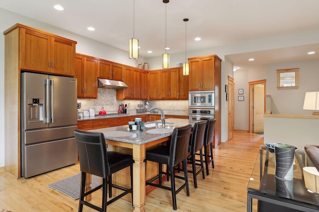 kitchen with under cabinet range hood, light wood-style flooring, stainless steel appliances, and a sink