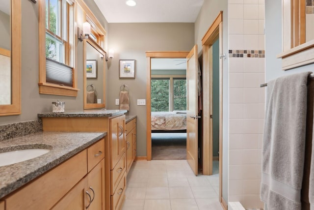 ensuite bathroom with tile patterned floors, a tile shower, vanity, and ensuite bathroom