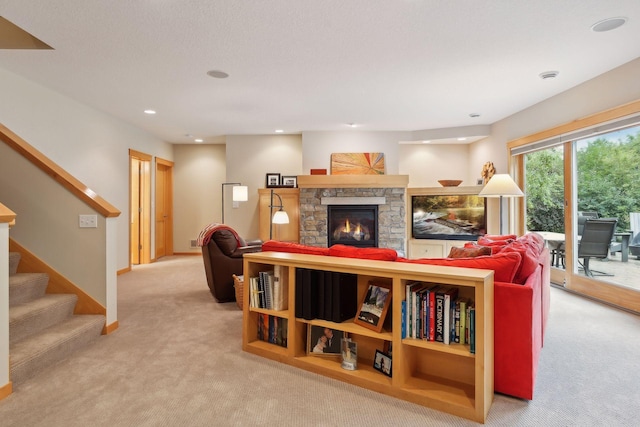 living room with baseboards, stairway, light carpet, a stone fireplace, and recessed lighting