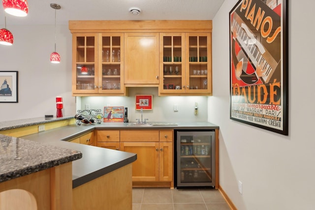 bar with light tile patterned floors, baseboards, wet bar, wine cooler, and pendant lighting