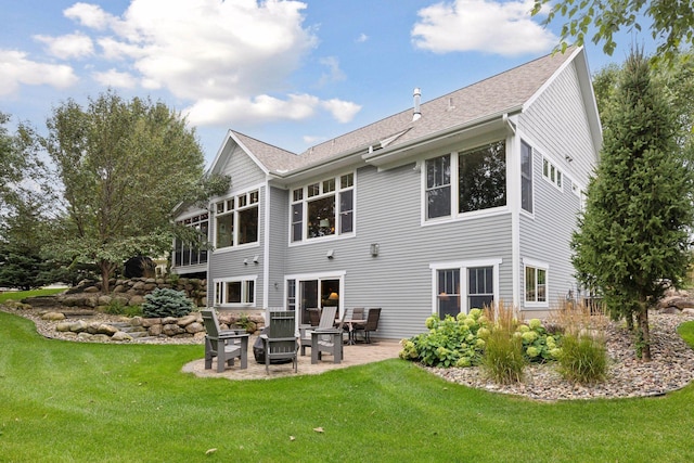 back of property with a yard, a patio area, and a shingled roof