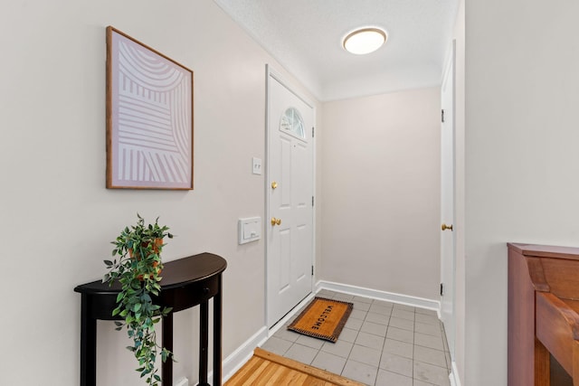 foyer entrance with a textured ceiling and light tile patterned floors