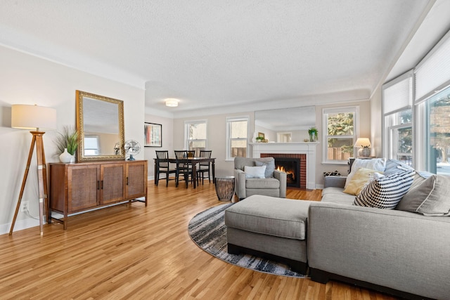 living room featuring light wood-type flooring, a brick fireplace, and a textured ceiling