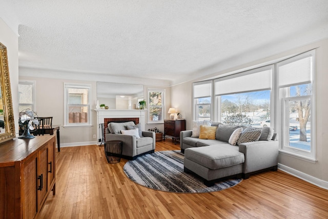 living room with a brick fireplace, plenty of natural light, and light hardwood / wood-style flooring