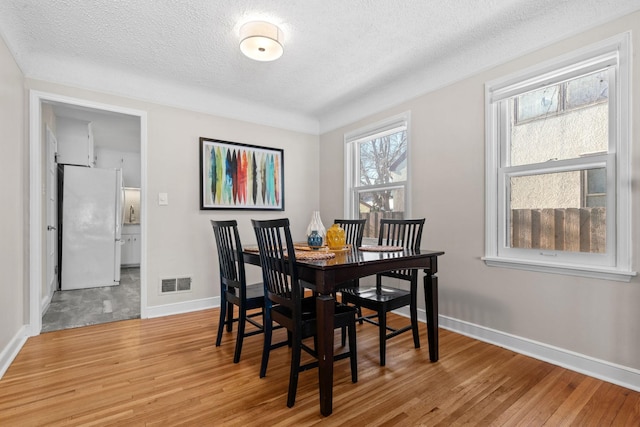 dining space with wood-type flooring and a textured ceiling