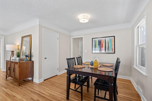 dining area with a textured ceiling and light hardwood / wood-style floors