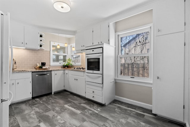 kitchen featuring light stone countertops, backsplash, white cabinets, and white appliances