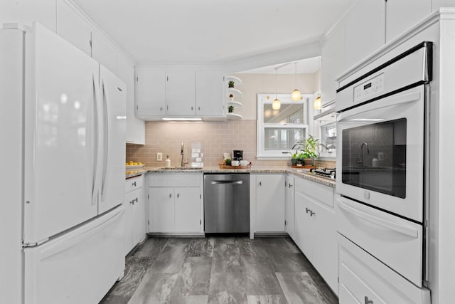 kitchen with appliances with stainless steel finishes, white cabinetry, tasteful backsplash, sink, and hanging light fixtures