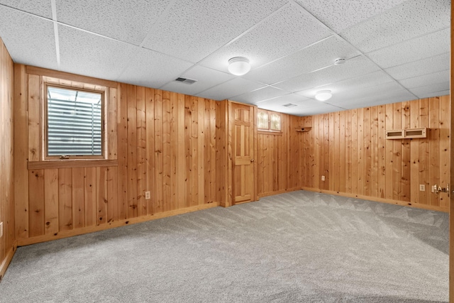 basement featuring a drop ceiling, wooden walls, and carpet floors