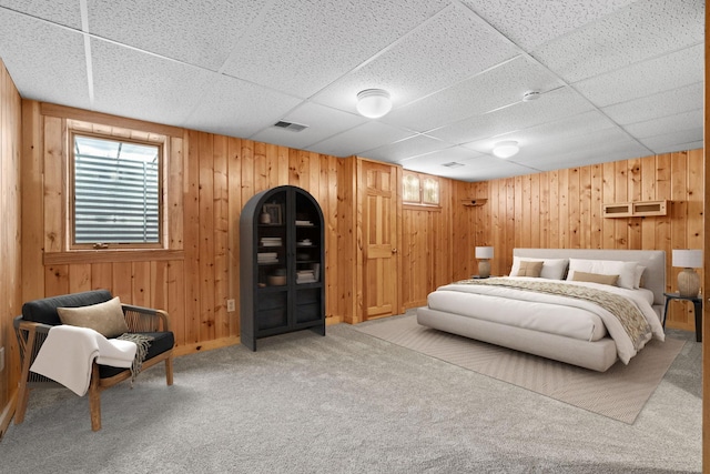 bedroom with a paneled ceiling, carpet floors, and wooden walls