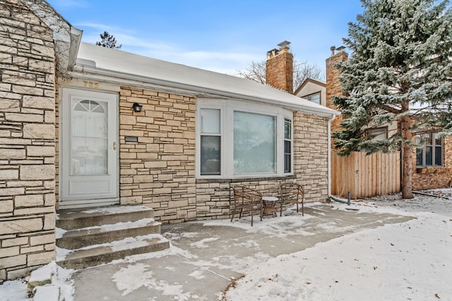 snow covered property entrance featuring a patio