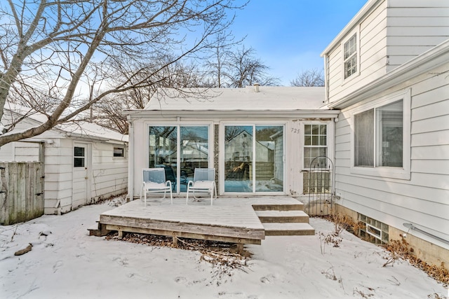 snow covered back of property with a wooden deck