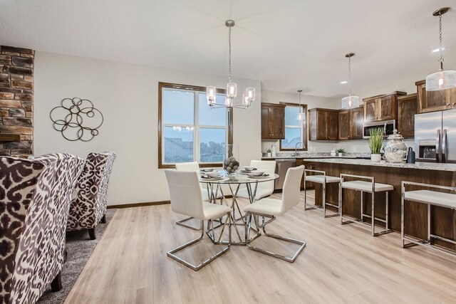 dining room featuring light hardwood / wood-style floors, sink, and an inviting chandelier