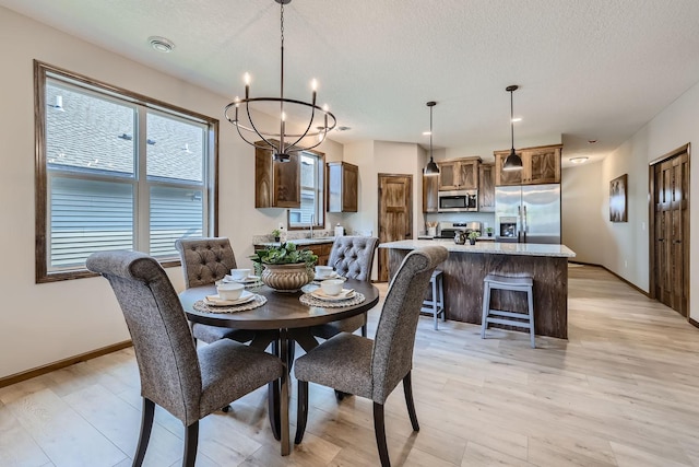 dining room featuring baseboards, light wood-type flooring, a chandelier, and a textured ceiling