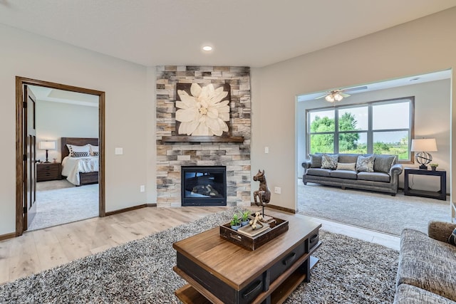 living room with a stone fireplace, baseboards, and wood finished floors