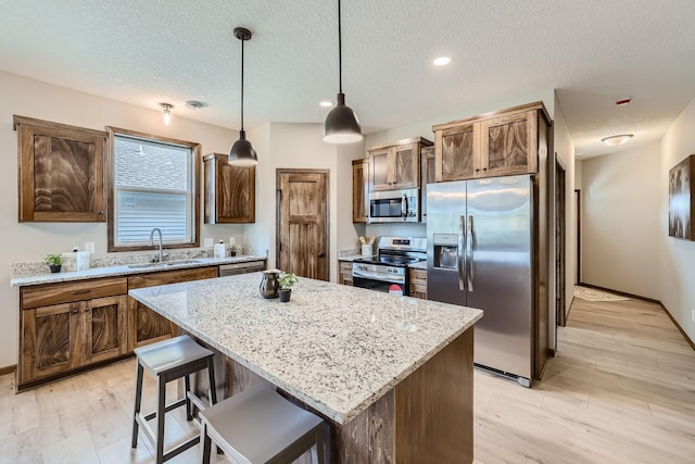 kitchen with a sink, a center island, light wood-type flooring, and stainless steel appliances