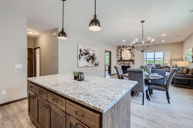 kitchen featuring decorative light fixtures, light wood-type flooring, open floor plan, and a fireplace