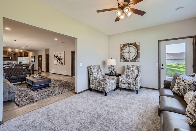 living room with light carpet, recessed lighting, ceiling fan with notable chandelier, and baseboards