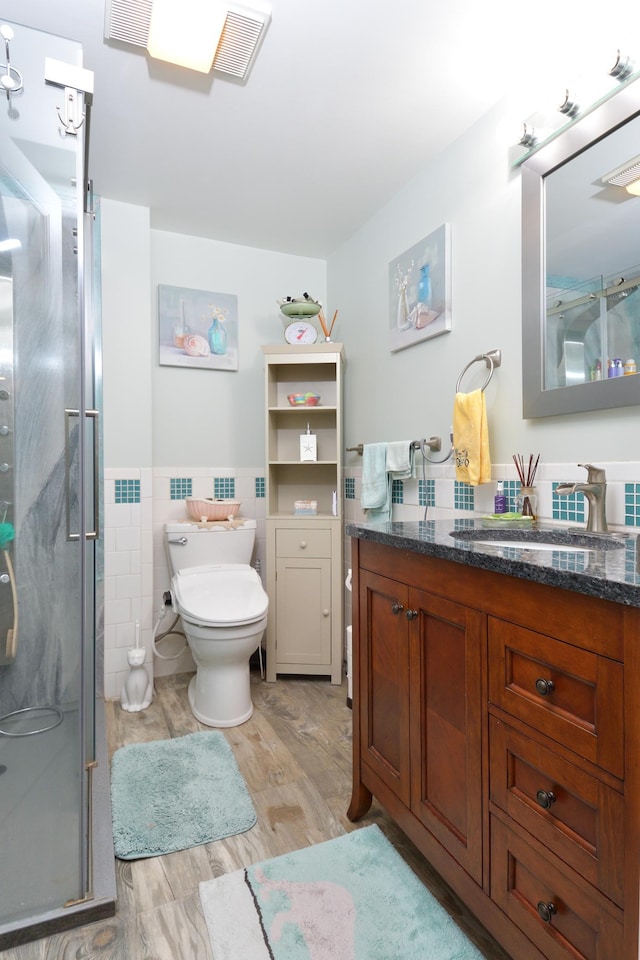 bathroom with tile walls, vanity, wood-type flooring, toilet, and walk in shower